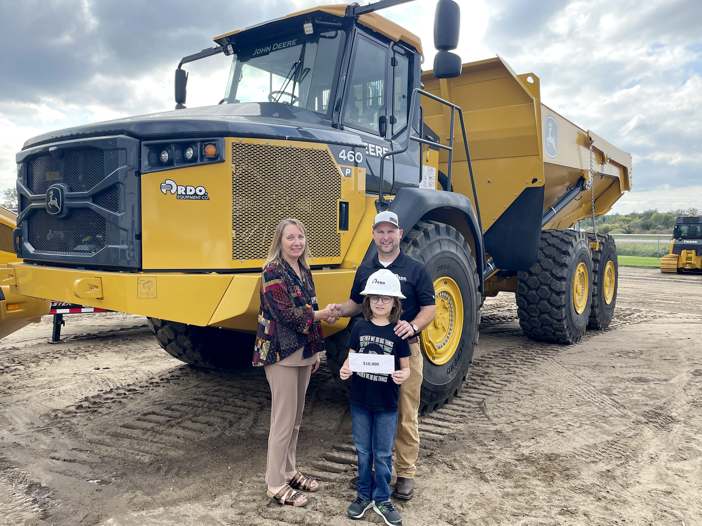 Jackie Johnson poses with Big and RDO Equipment Co. employee David Henkel and his Little, Alex, while accepting a check